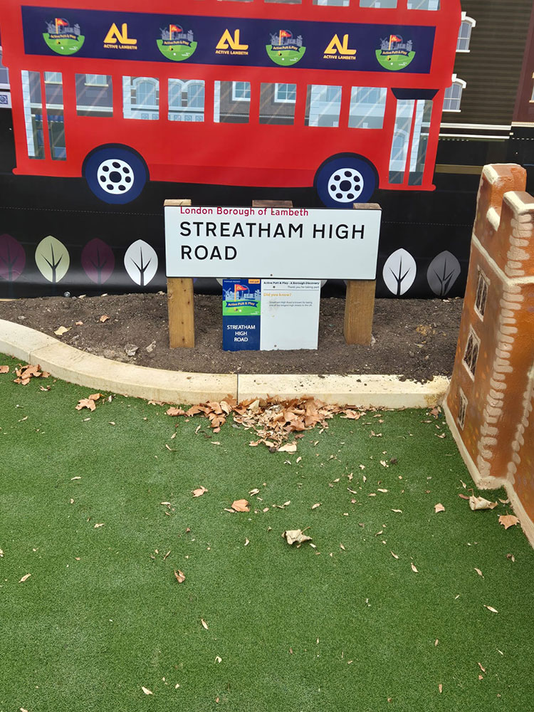 Lambeth-themed bus artwork beside a putting hole